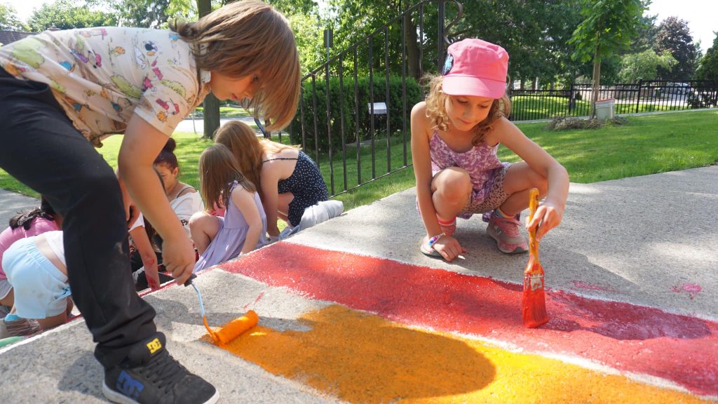 Children painting rainbow colours on the front steps at Trillium.
