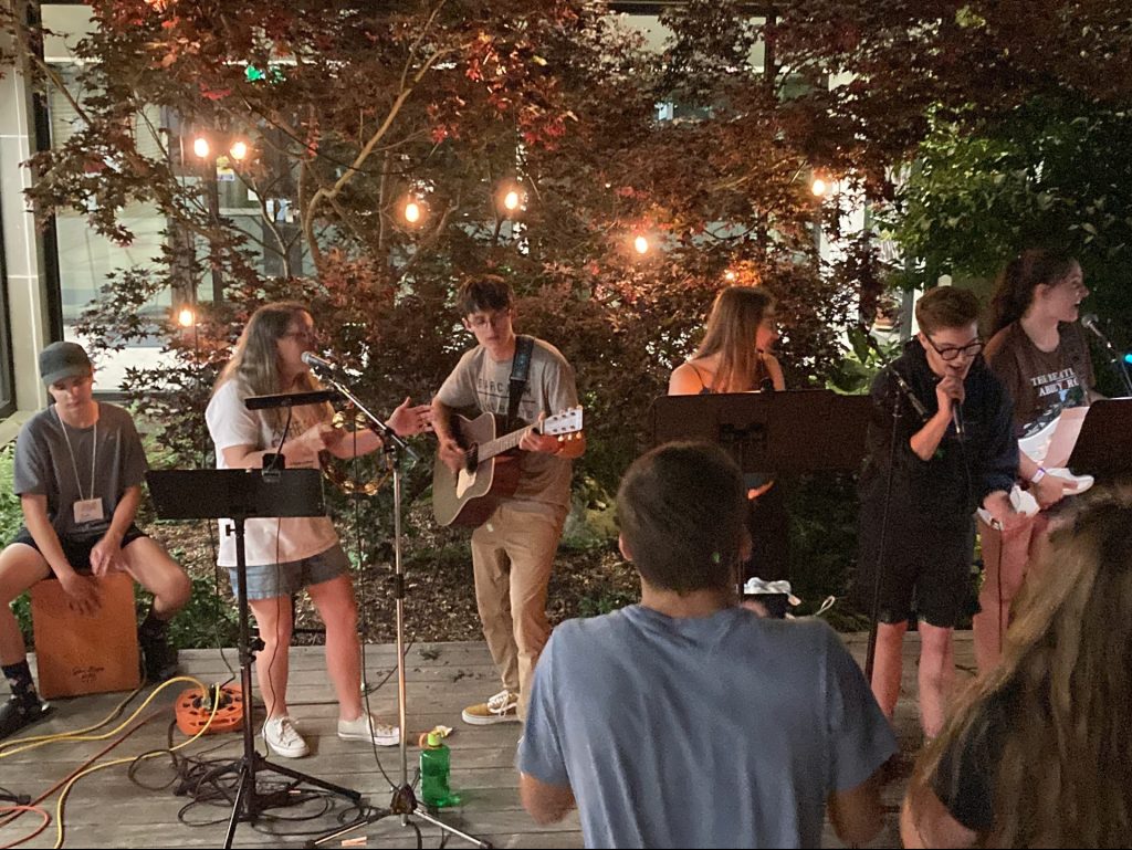 Youth musicians lead evening worship in outdoor courtyard.